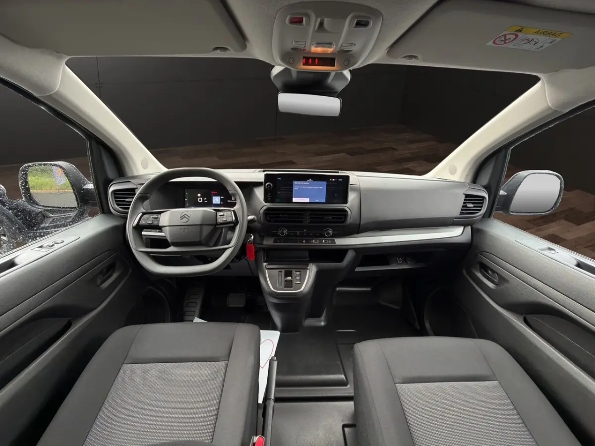 Vue intérieure avant du Citroën Jumpy XL gris foncé, tableau de bord moderne avec écran tactile central et volant multifonctions.
