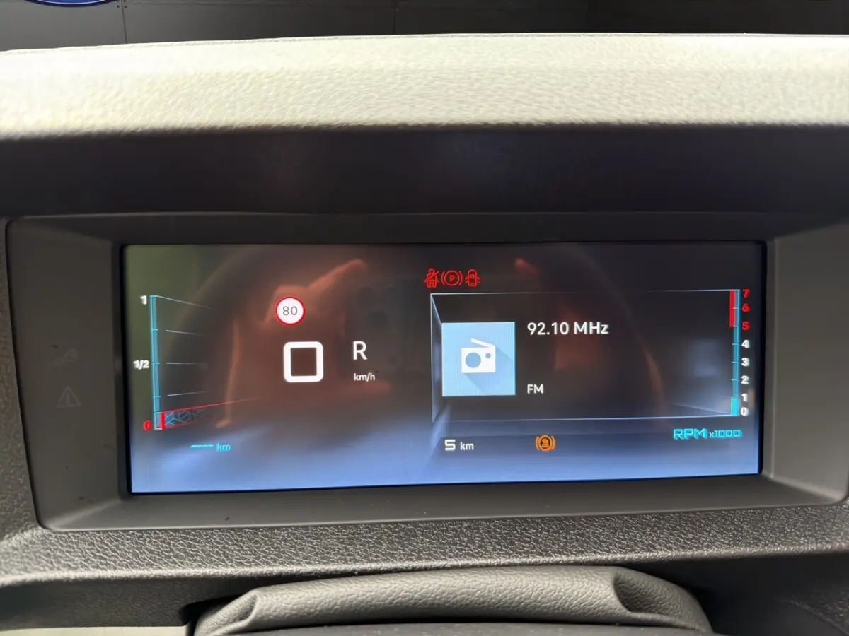 Affichage numérique du tableau de bord du Citroën Jumpy XL gris foncé, montrant la vitesse, la radio FM et le régime moteur.