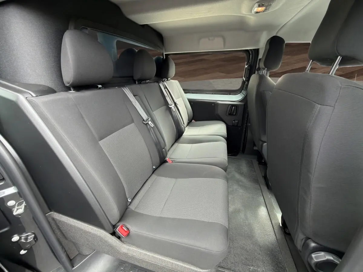 Vue intérieure côté droit sur la banquette arrière grise du Citroën Jumpy XL 2026 avec cloison vitrée et ceintures visibles.