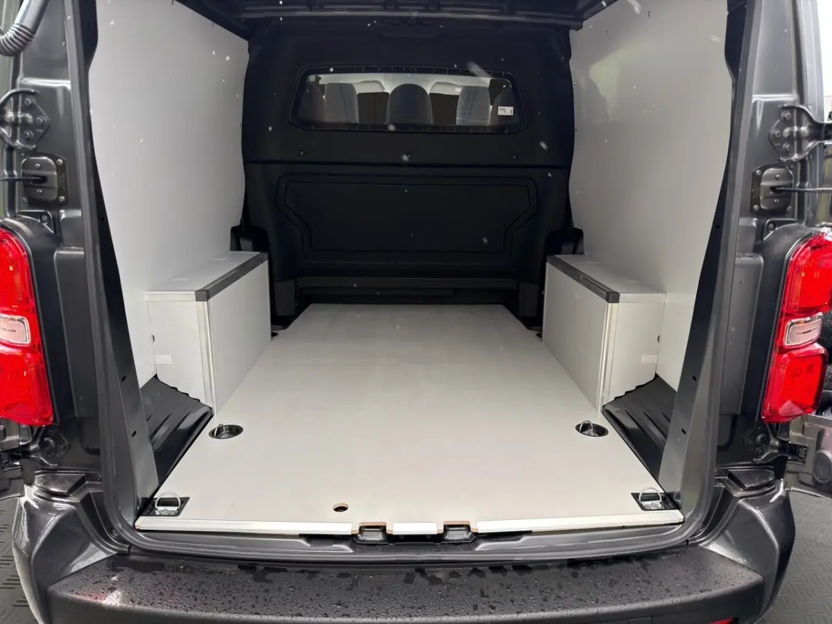 Vue arrière du Citroën Jumpy XL gris foncé, montrant l’espace de chargement avec cloison vitrée et kit bois.