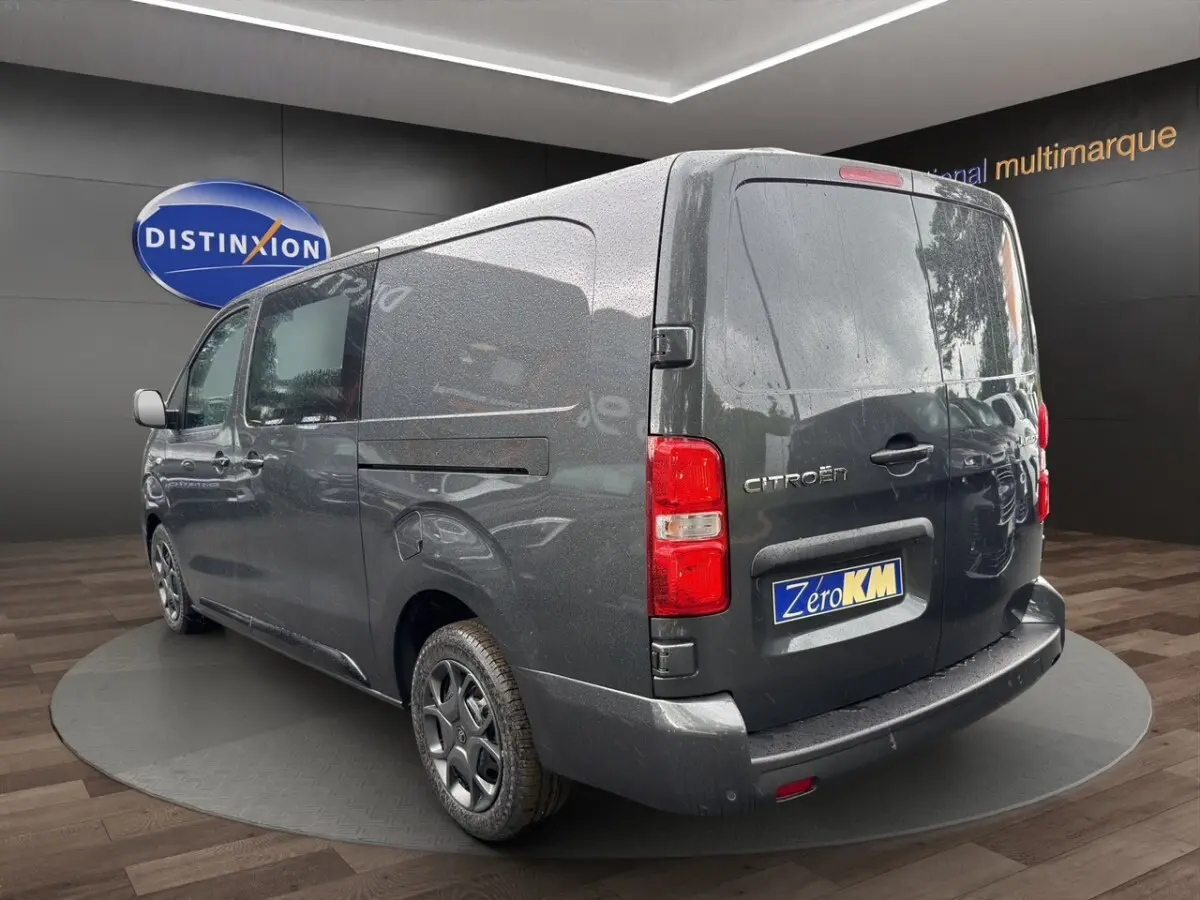 Vue 3/4 arrière droite d’un Citroën Jumpy XL gris foncé avec porte latérale coulissante et feux arrière rouges.