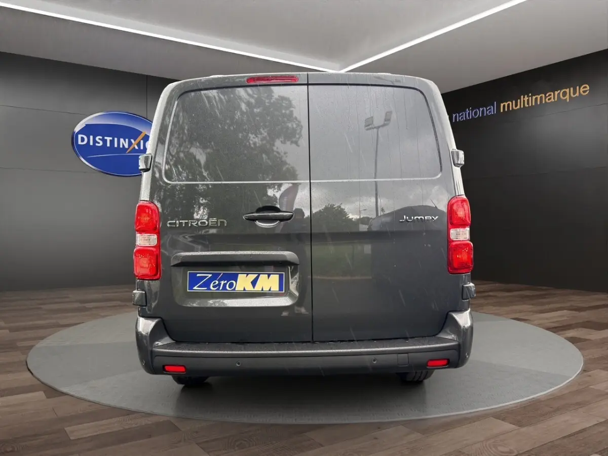 Vue arrière d'un Citroën Jumpy gris foncé avec portes battantes et feux rouges en intérieur showroom.