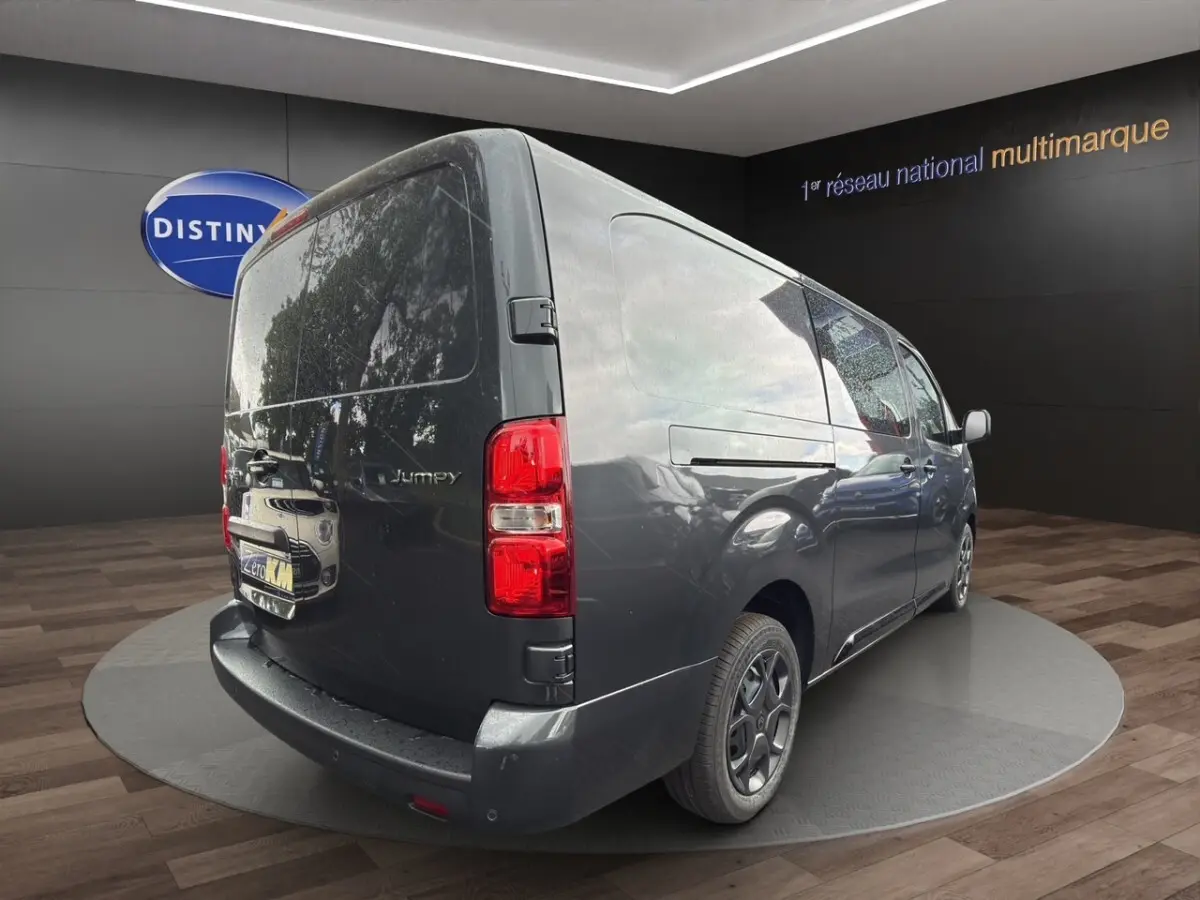 Vue 3/4 arrière droit d'un Citroën Jumpy XL gris foncé avec feux arrière rouges et jantes noires.