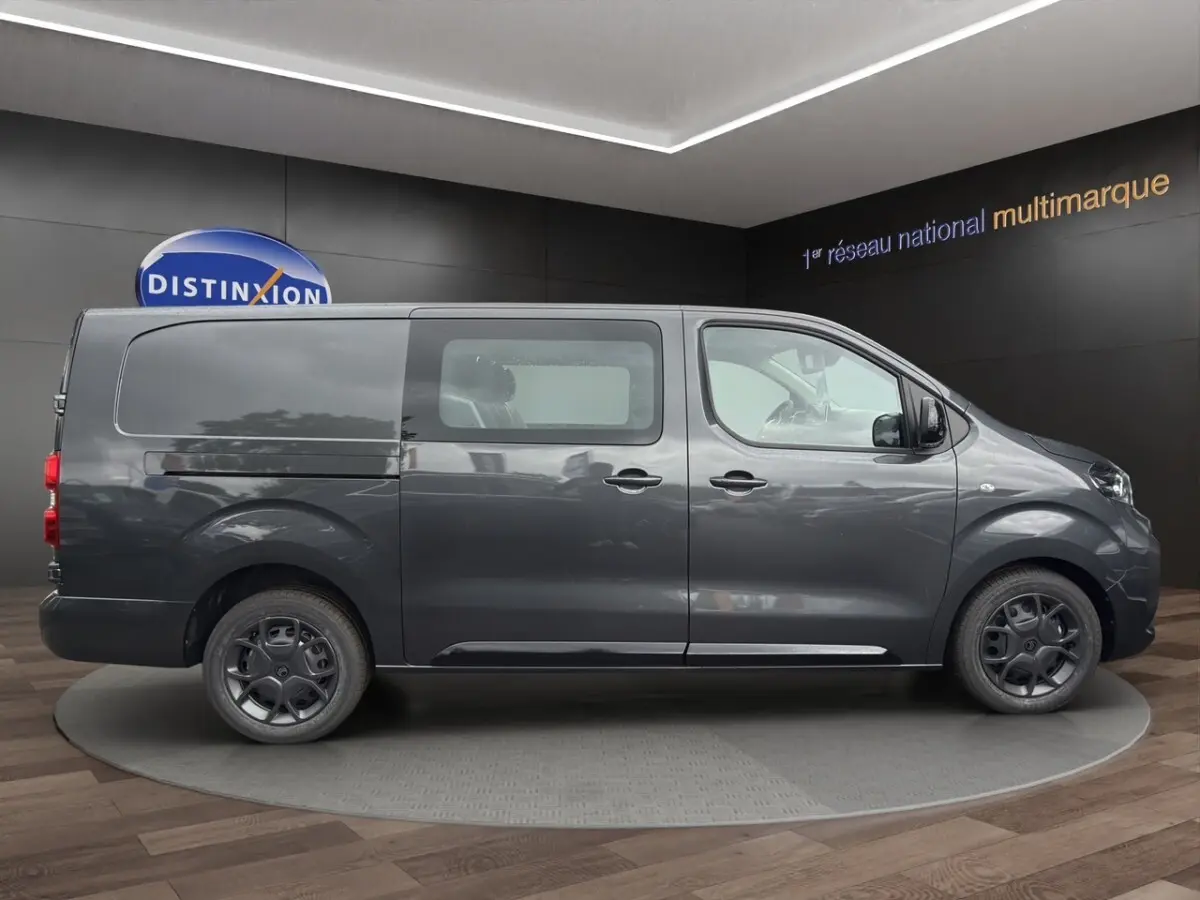 Vue latérale droite d’un Citroën Jumpy XL gris foncé avec vitres avant et porte coulissante en showroom.