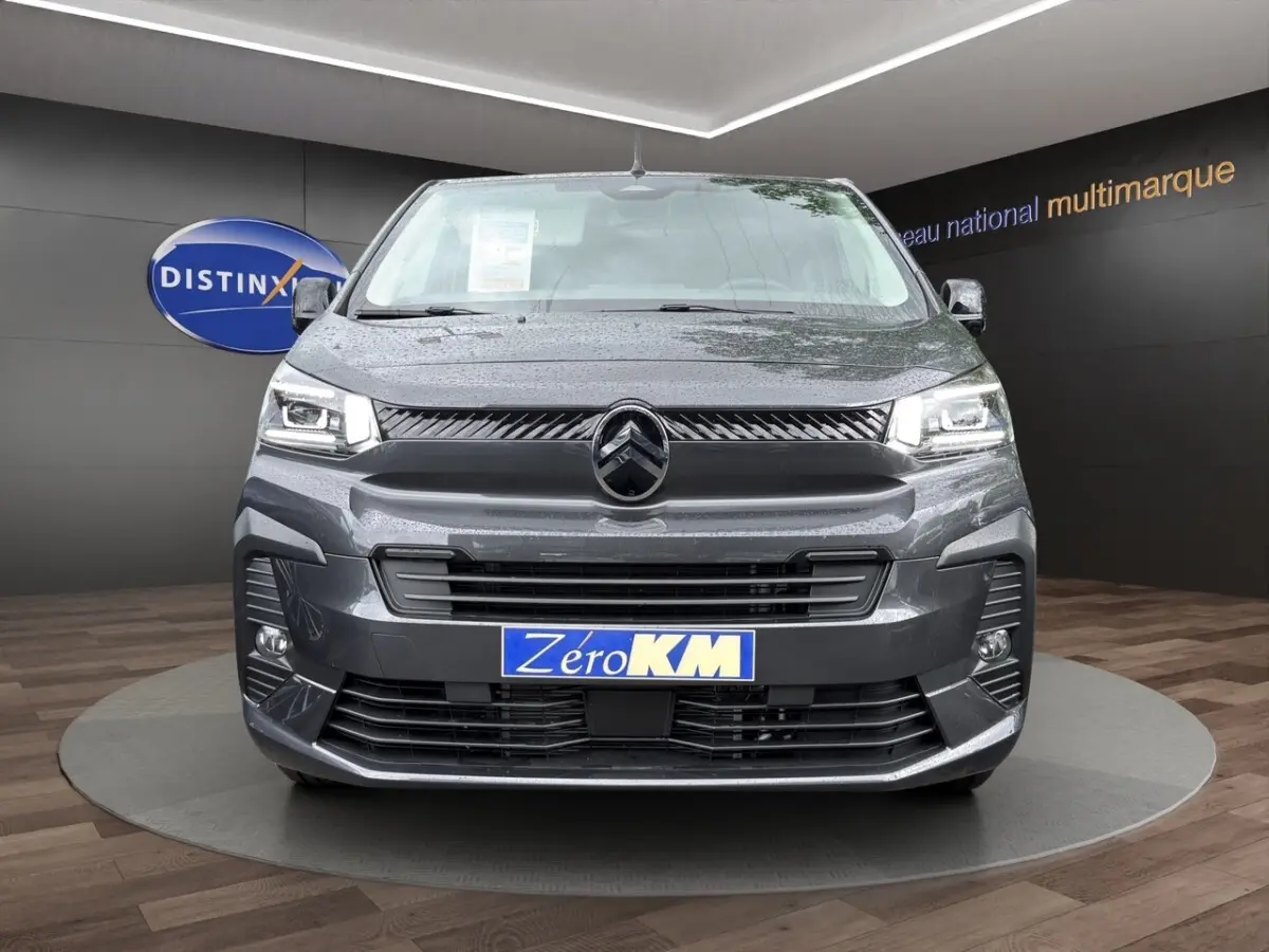 Vue de face d'un Citroën Jumpy XL gris foncé avec phares LED et calandre noire brillante dans un showroom.