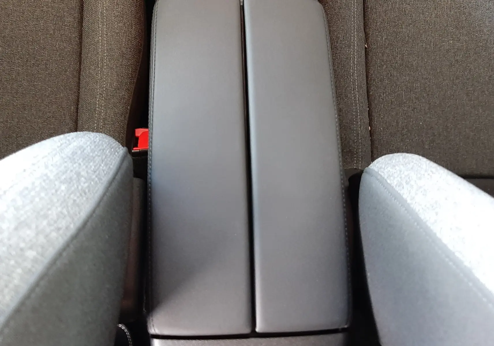 Vue plongeante sur l'accoudoir central gris et les sièges en tissu gris du Citroën C5 Aircross 2025.