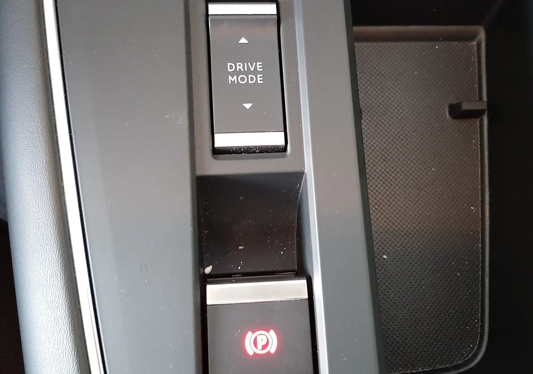 Vue rapprochée du bouton de mode de conduite et frein à main électronique sur la console centrale noire du Citroën C5 Aircross.