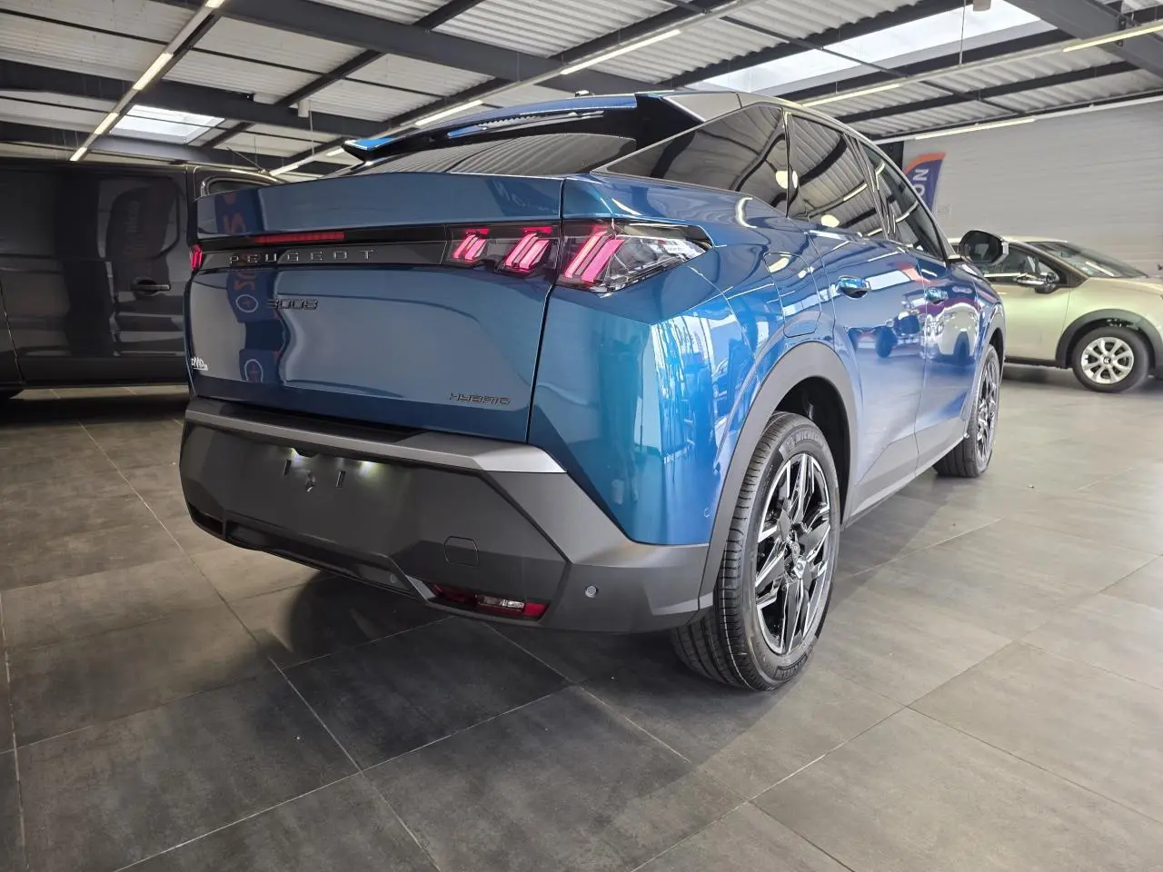 Vue 3/4 arrière droite du Peugeot 3008 hybride bleu métallisé avec feux arrière à LED en forme de griffes et jantes alliage 18 pouces.