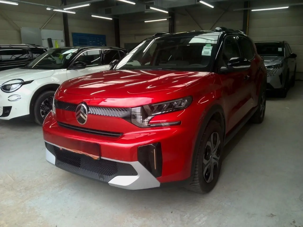 SUV Citroën C3 Aircross rouge Elixir avec toit noir, vu en 3/4 avant droit dans un garage intérieur.
