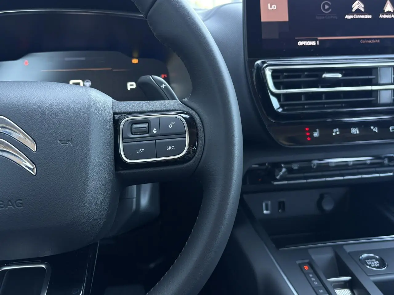Gros plan sur le volant et la console centrale noire du Citroën C5 Aircross Hybrid 2025 avec commandes intégrées et écran tactile.