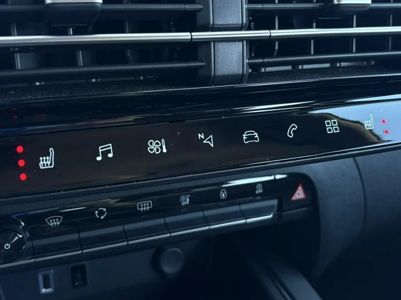 Détail de la console centrale noire brillante du Citroën C5 Aircross Hybrid 2025 avec commandes tactiles et voyants rouges allumés.