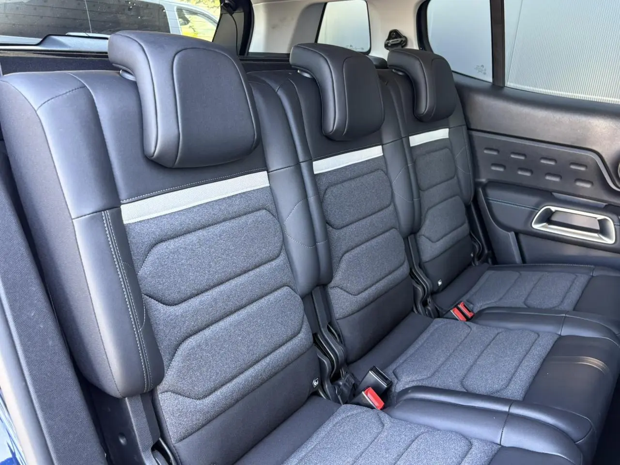 Vue intérieure des trois sièges arrière indépendants en tissu gris et cuir noir du Citroën C5 Aircross Hybrid 2025.