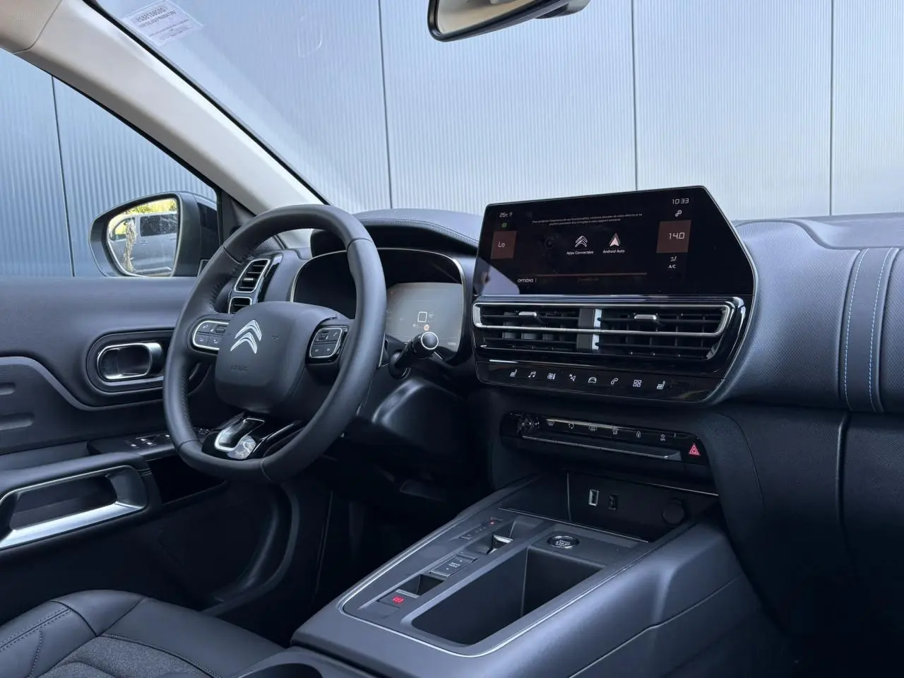 Intérieur du Citroën C5 Aircross Hybrid 2025, vue côté conducteur, tableau de bord noir avec écran tactile et volant cuir.