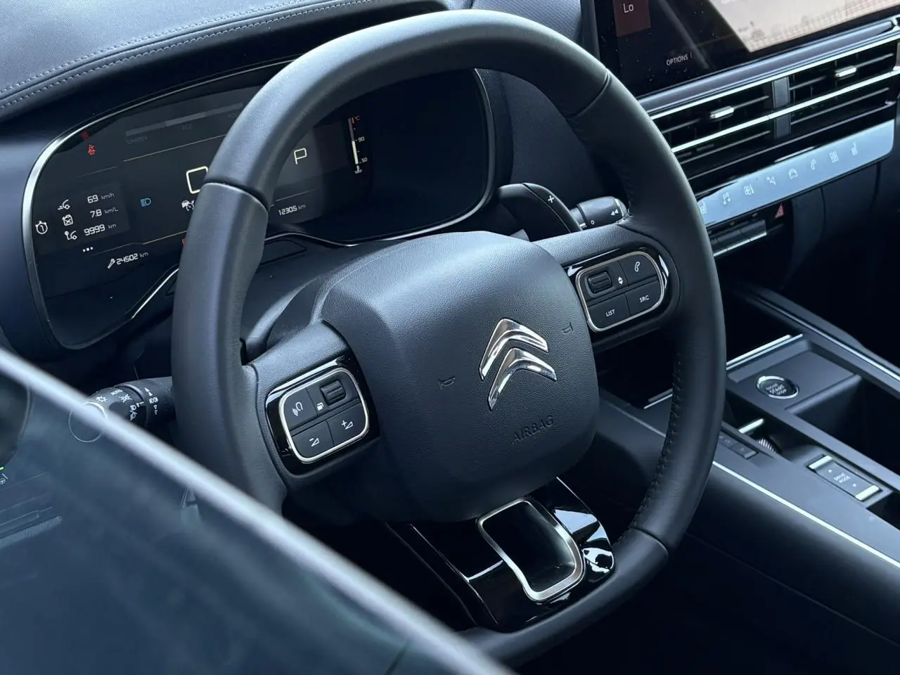 Vue rapprochée du volant noir et du tableau de bord numérique du Citroën C5 Aircross Hybrid 2025.