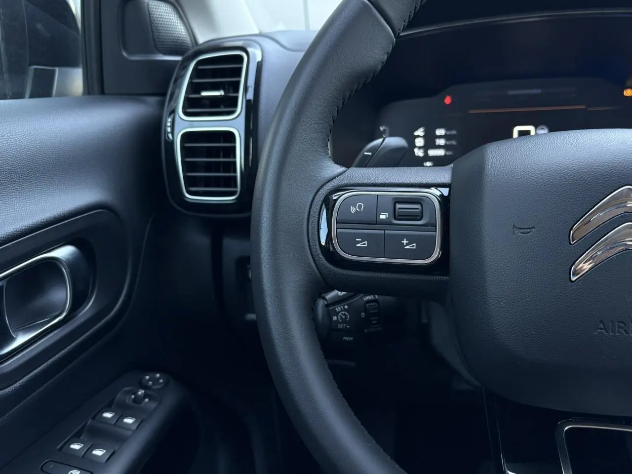 Vue rapprochée du volant et de la portière gauche du Citroën C5 Aircross Hybrid, intérieur noir avec commandes au volant.