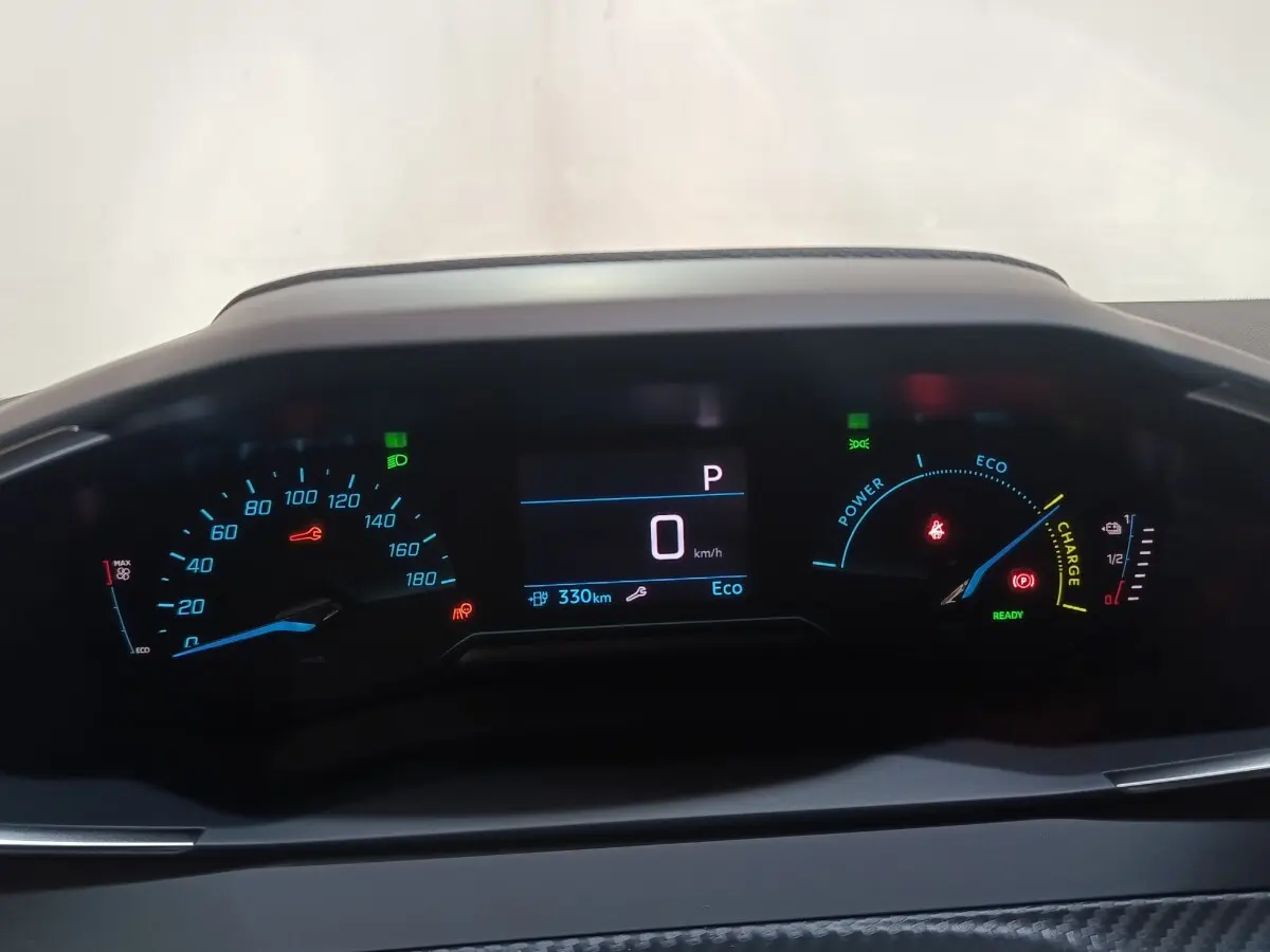 Tableau de bord numérique de Peugeot 208 électrique 2024, affichage vitesse, autonomie et charge batterie en vue frontale.