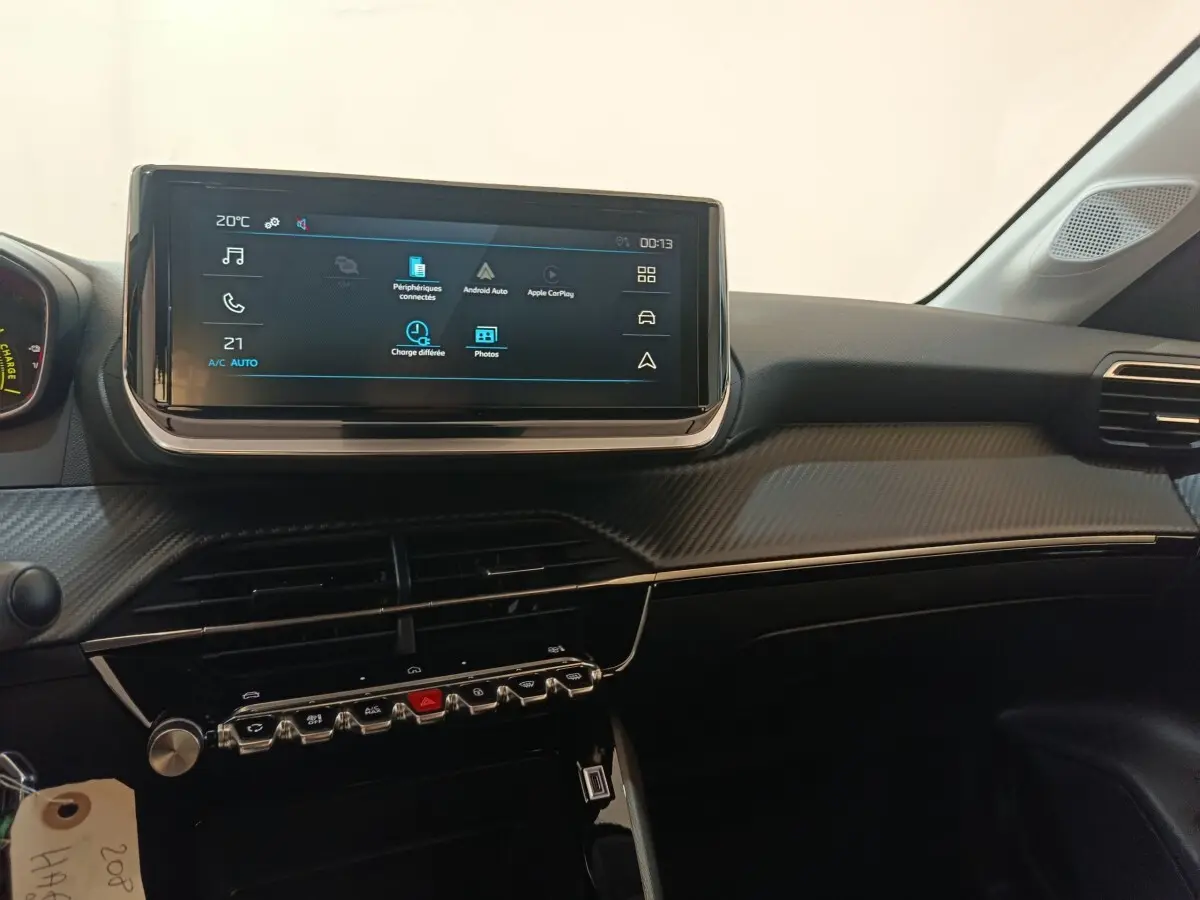 Vue intérieure du tableau de bord de la Peugeot 208 électrique 2024, écran tactile central et finition carbone gris.
