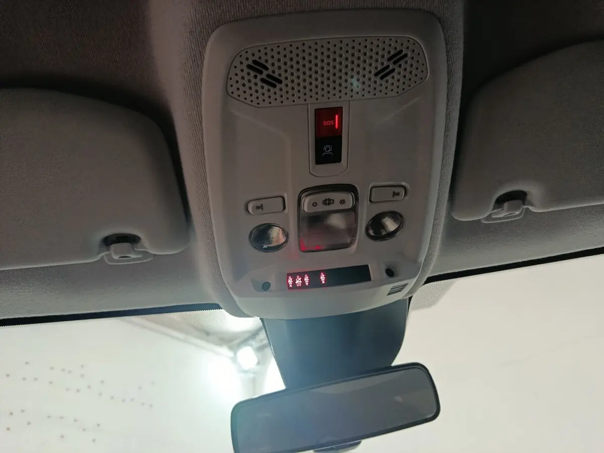 Vue intérieure du plafond avant de la Peugeot 208 électrique 2024, avec panneau de commandes et miroir central gris clair.
