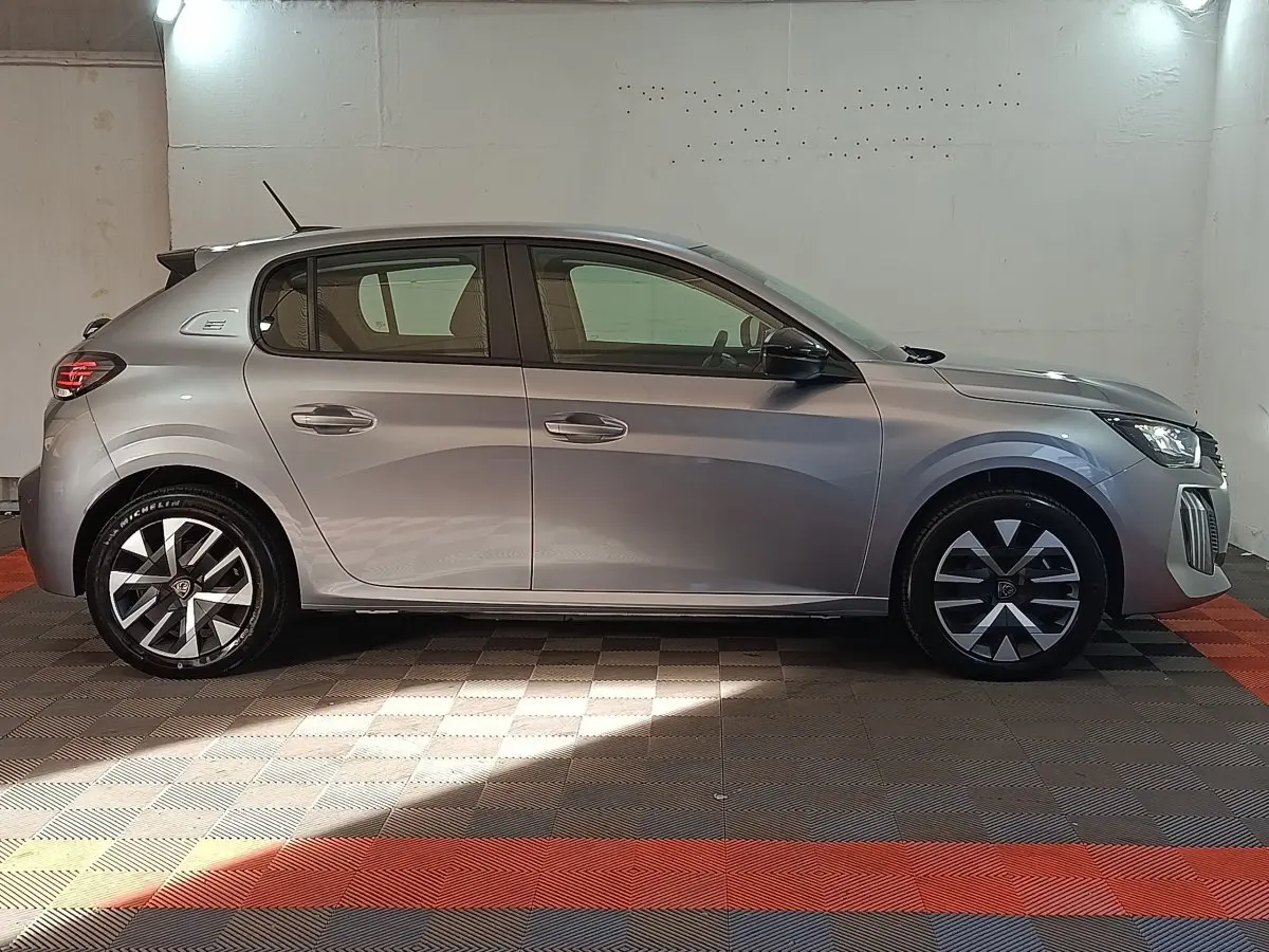 Peugeot 208 électrique gris clair vue de profil côté gauche, avec jantes stylisées et feux arrière LED.