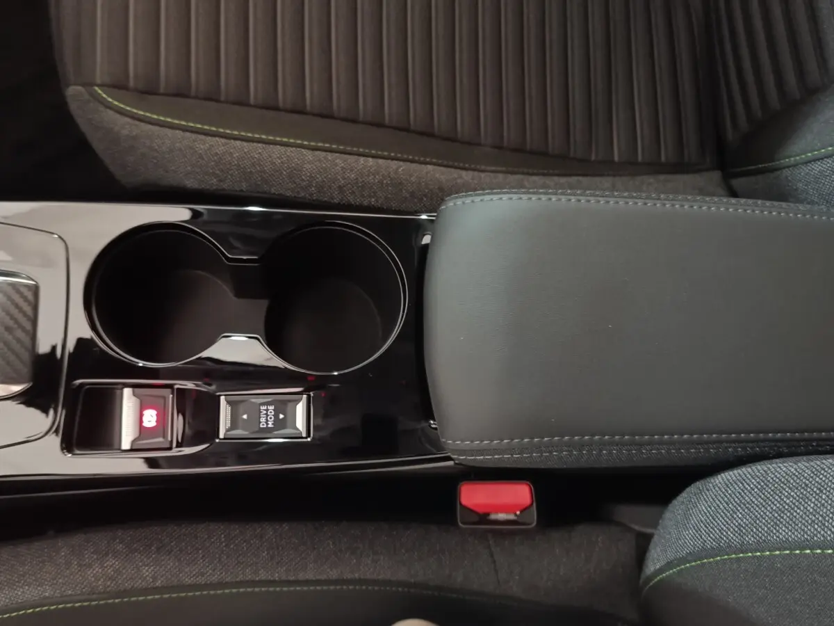 Vue rapprochée de la console centrale noire avec frein à main électrique et bouton Drive Mode sur Peugeot 208 électrique gris clair.