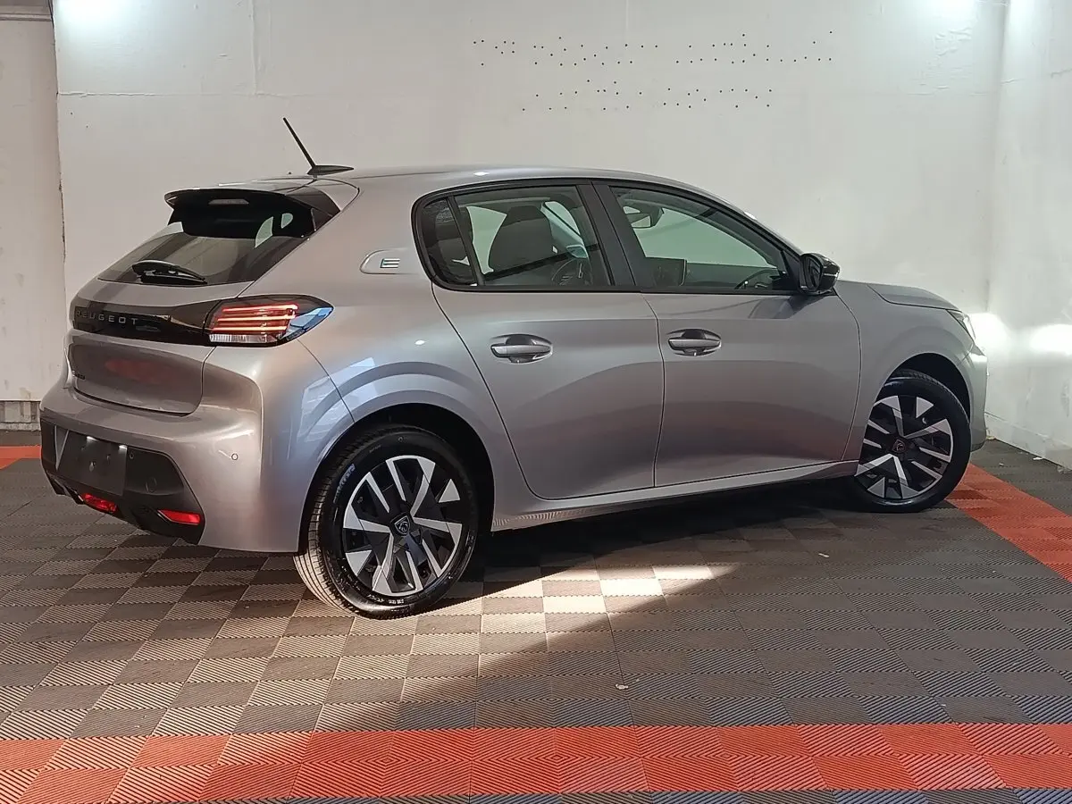 Peugeot 208 électrique gris clair vue de profil côté droit, avec jantes alliage et feux arrière LED distinctifs.