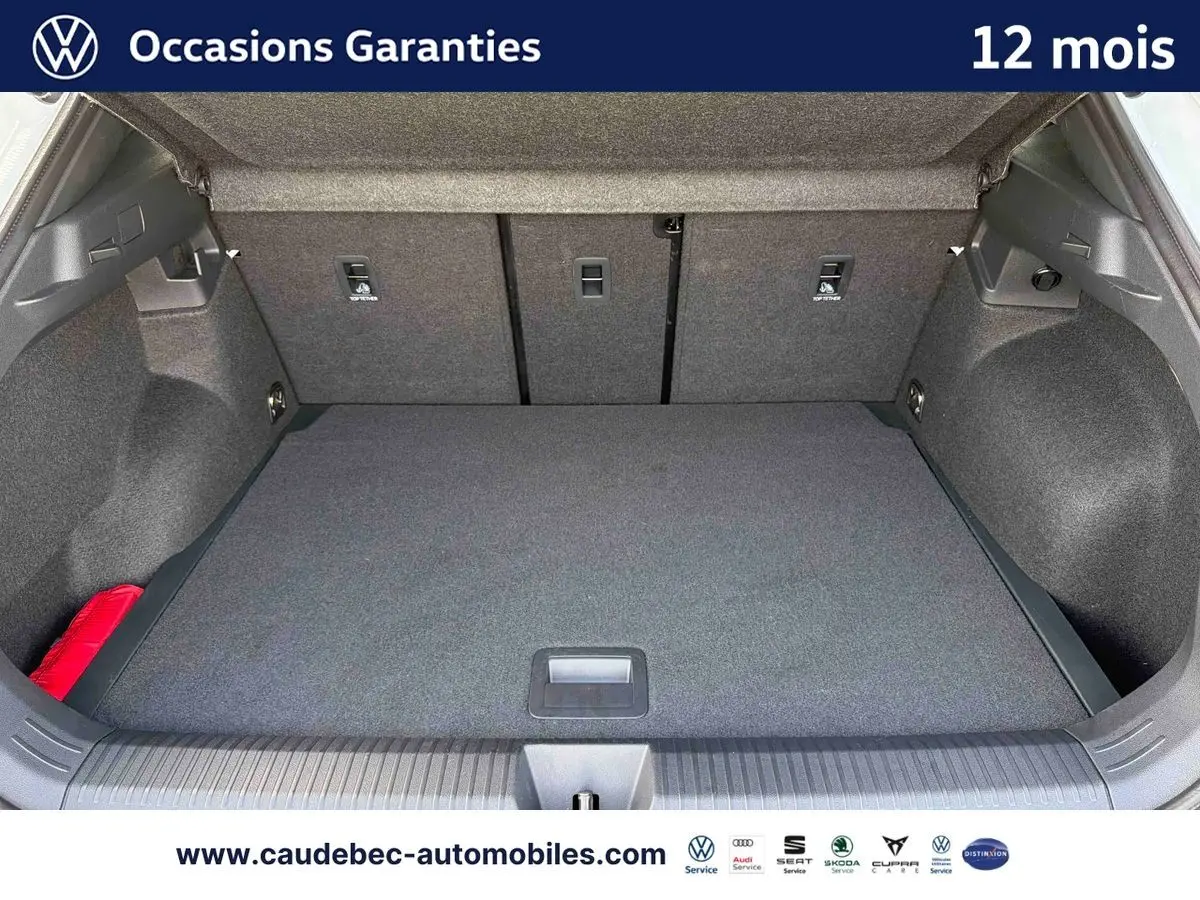 Coffre ouvert du Volkswagen T-Roc blanc, vue de l'arrière montrant un espace de chargement propre et spacieux.