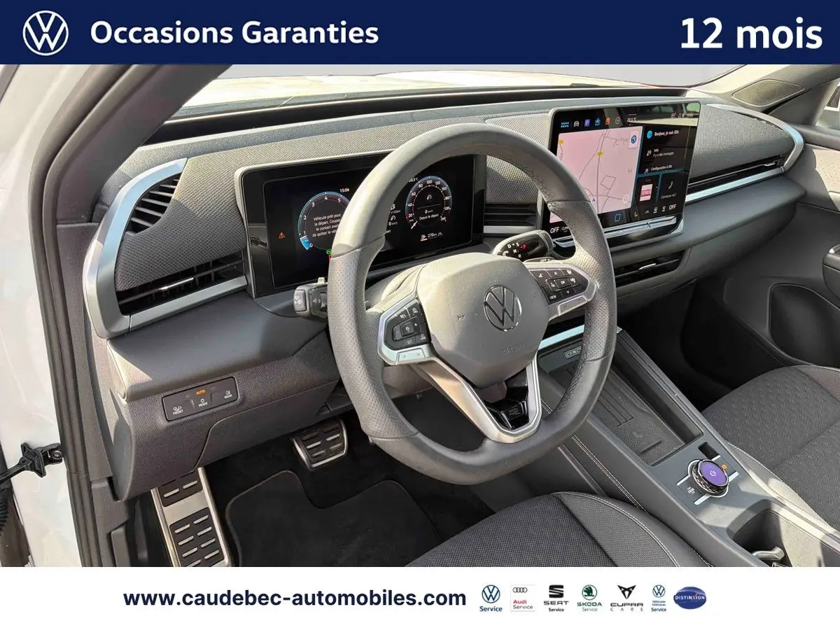 Vue intérieure côté conducteur du Volkswagen T-Roc blanc 2025, volant multifonction cuir et écran tactile central visible.