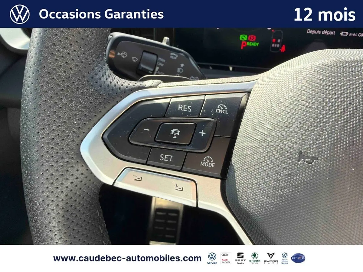 Gros plan sur le volant multifonction cuir noir perforé du Volkswagen T-Roc blanc, avec commandes de régulateur de vitesse.