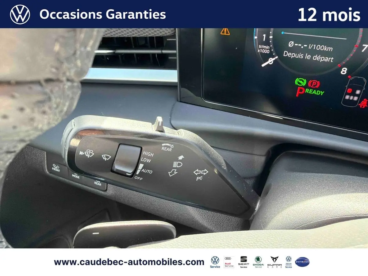 Gros plan sur la commande d’essuie-glace et tableau de bord numérique du Volkswagen T-Roc blanc, intérieur moderne.