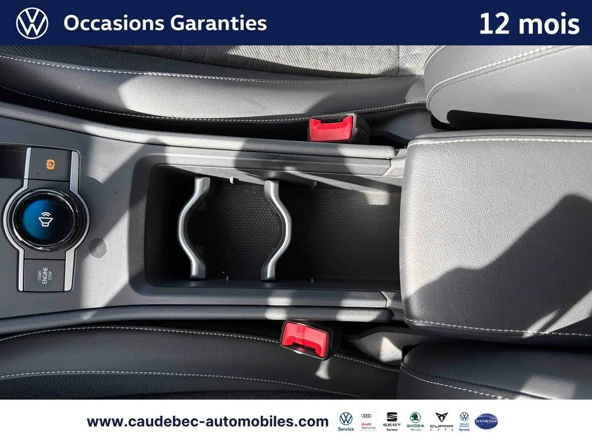 Vue plongeante sur la console centrale noire du Volkswagen T-Roc 2025 avec bouton Start/Stop et porte-gobelets.