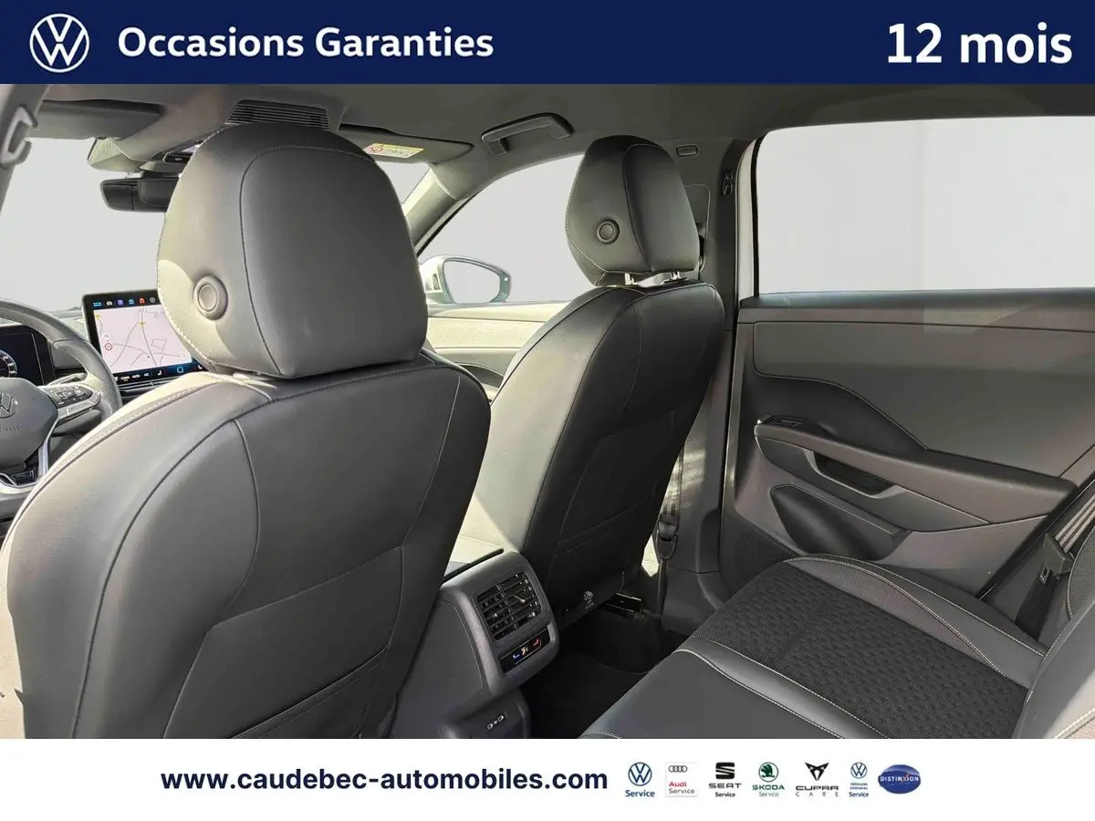 Vue intérieure arrière du Volkswagen T-Roc 2025 avec sièges en cuir noir et console centrale avec aérateurs et commandes climatiques.