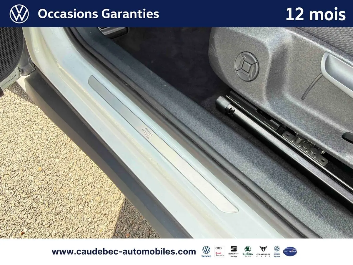 Vue rapprochée de l'encadrement de porte côté conducteur du Volkswagen T-Roc blanc, avec seuil de porte siglé R-Line.