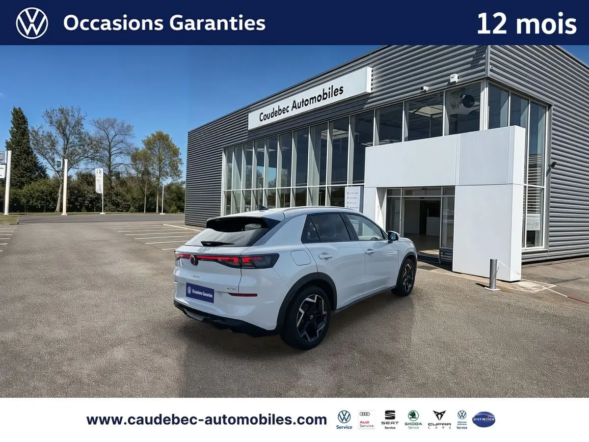 Volkswagen T-Roc blanc vue 3/4 arrière droit, avec feux LED arrière et jantes alliage noires brillantes, devant concession.