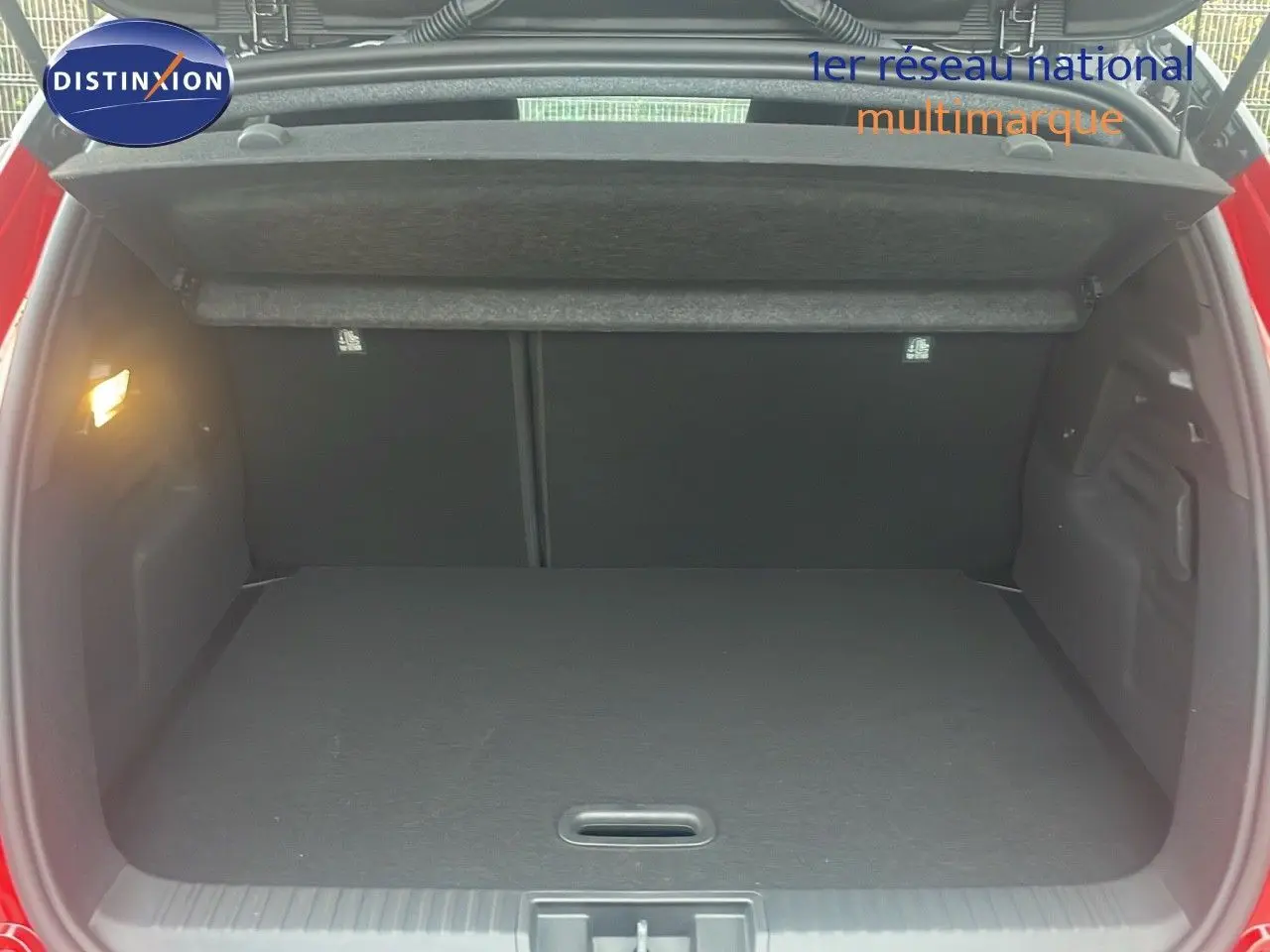 Coffre ouvert du Renault Captur E-Tech hybride rouge passion avec toit noir, vue arrière montrant l’espace de chargement vide.