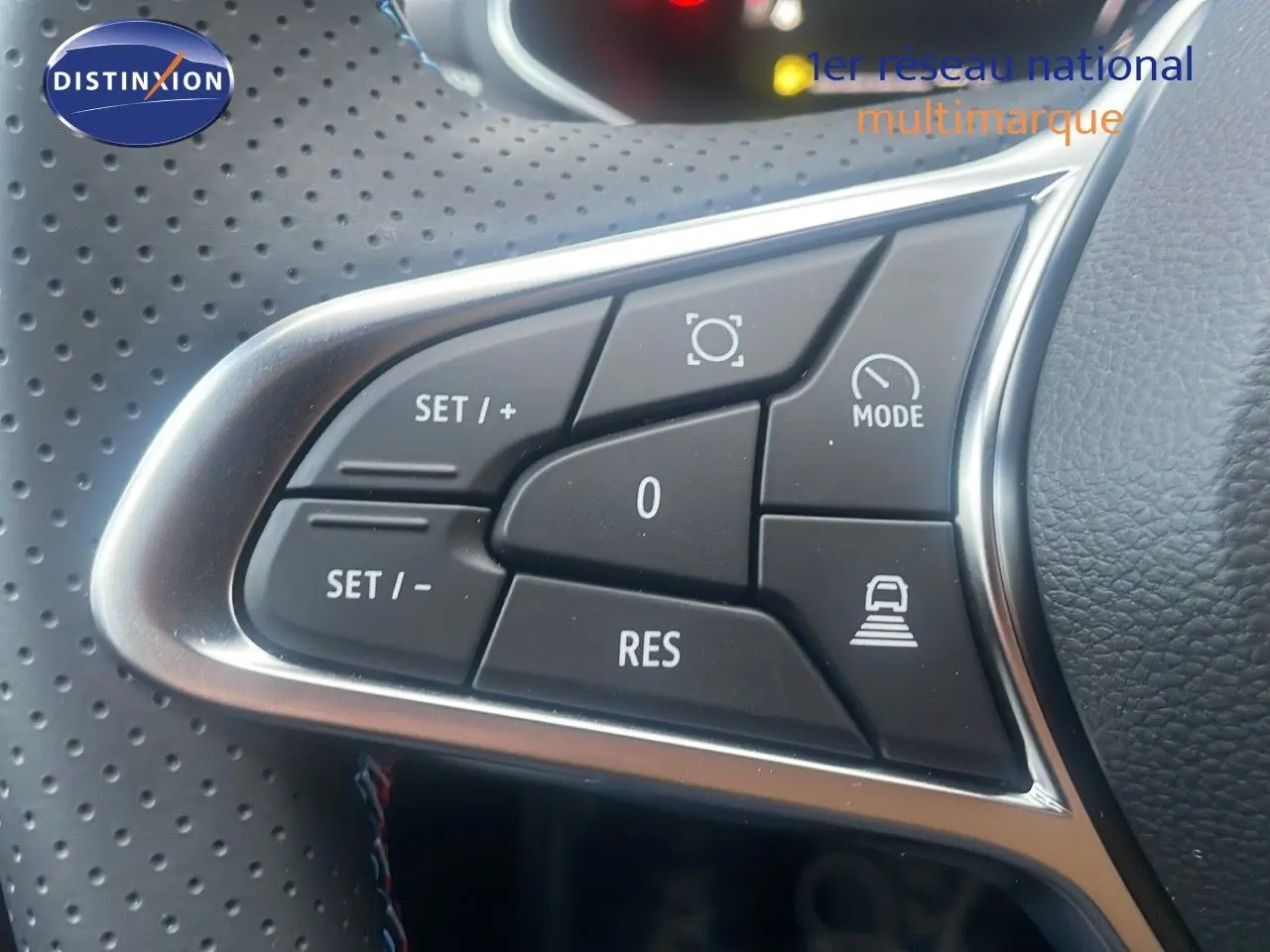 Gros plan sur les commandes au volant en cuir perforé noir du Renault Captur E-Tech hybride rouge passion toit noir.