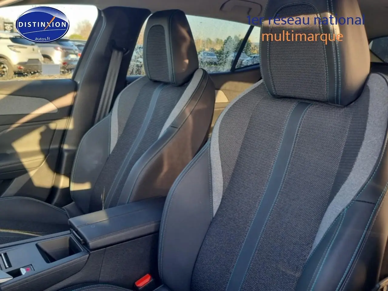 Vue intérieure des sièges avant gris foncé et tissu avec surpiqûres bleues du Peugeot 408 Hybrid 145 allure e-dcs6.