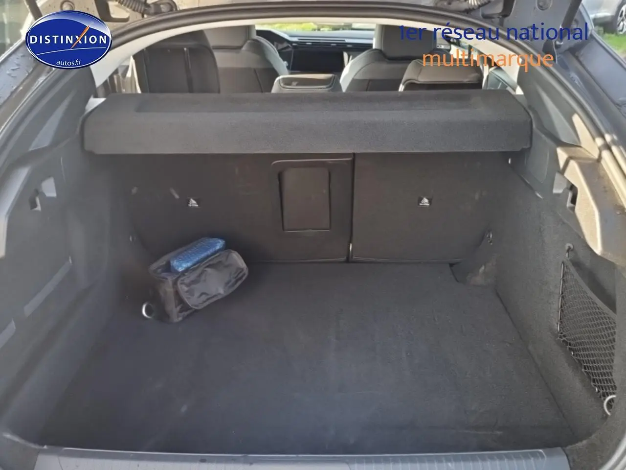 Coffre ouvert d'une Peugeot 408 Hybrid 145 allure gris sélénite, montrant l'espace de chargement et la banquette arrière.