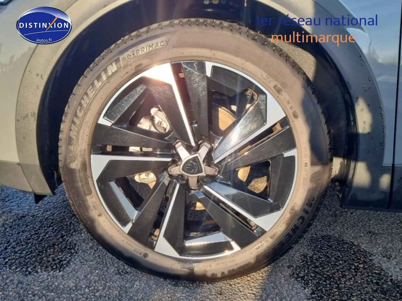 Gros plan sur la jante alu bicolore et le pneu Michelin d'une Peugeot 408 gris sélénite côté arrière droit.