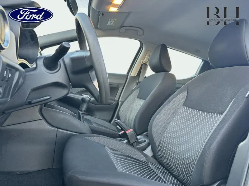 Vue intérieure côté conducteur de la Nissan Micra 2018 avec sièges tissu noir et gris, volant et levier de vitesses manuelle.