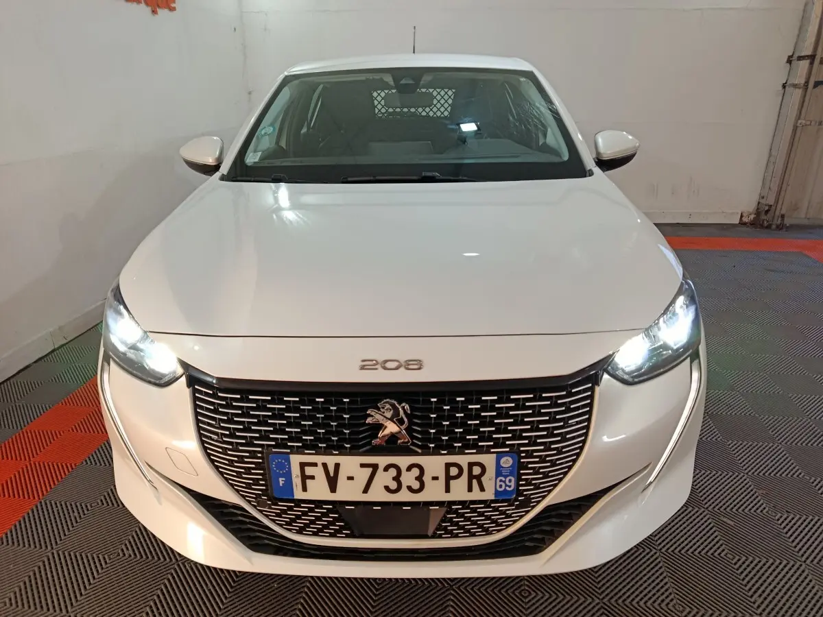Vue de face d'une Peugeot 208 électrique Active Business blanche avec phares allumés et calandre noire distinctive.