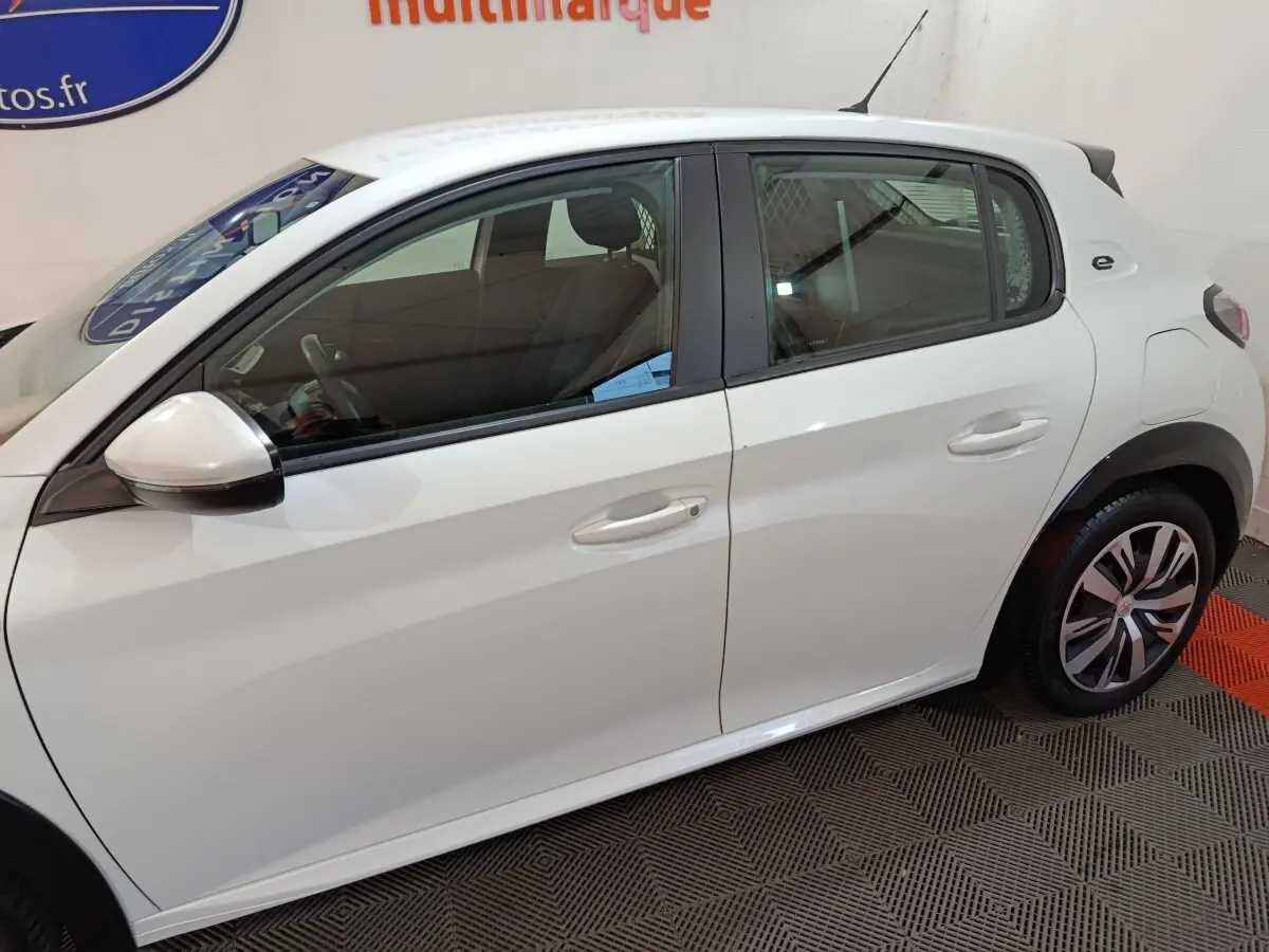 Vue de profil côté gauche d'une Peugeot 208 électrique Active Business blanche avec jantes spécifiques et logo "e" arrière.