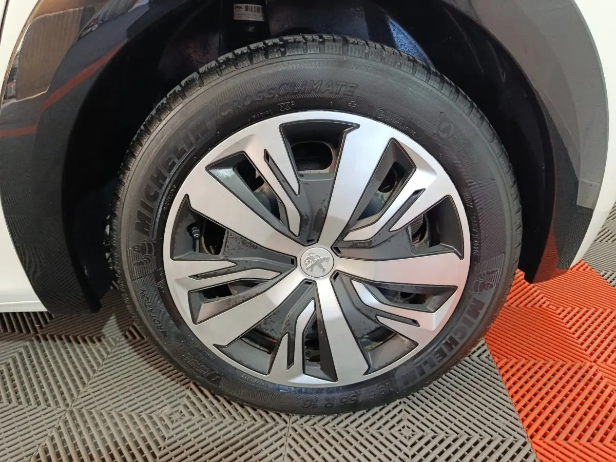 Gros plan sur la roue avant droite de la Peugeot 208 électrique blanche, avec jante en alliage au design moderne.