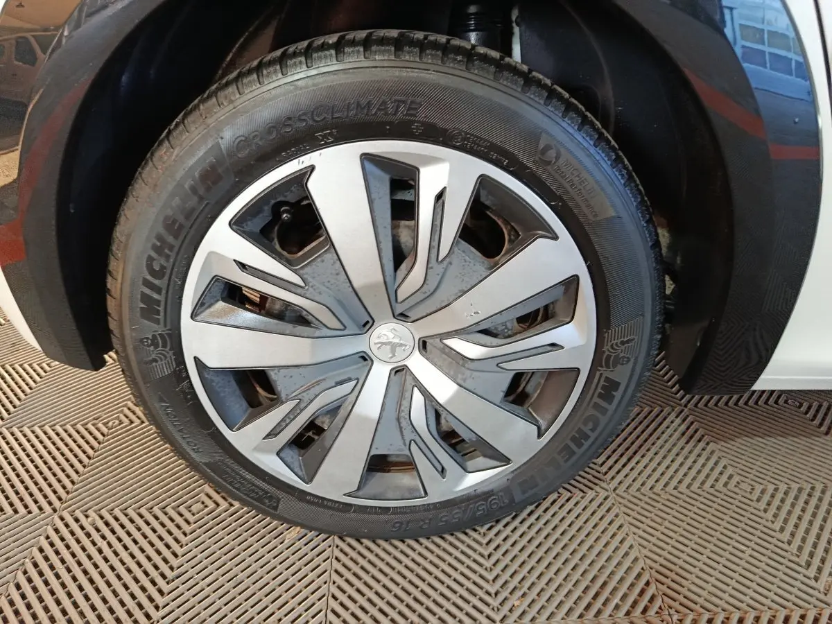Gros plan sur la roue avant droite d'une Peugeot 208 électrique blanche avec jante spécifique et pneu Michelin.