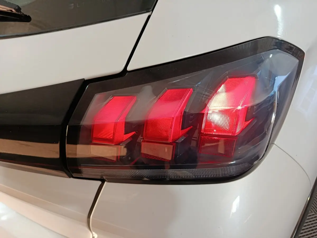 Gros plan sur le feu arrière droit rouge de la Peugeot 208 électrique Active Business blanche, vue arrière côté droit.