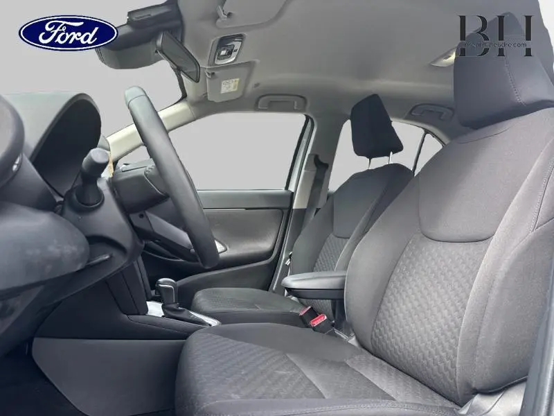 Vue intérieure côté gauche montrant les sièges avant gris et le volant multifonction d'une Toyota Yaris Cross blanche.