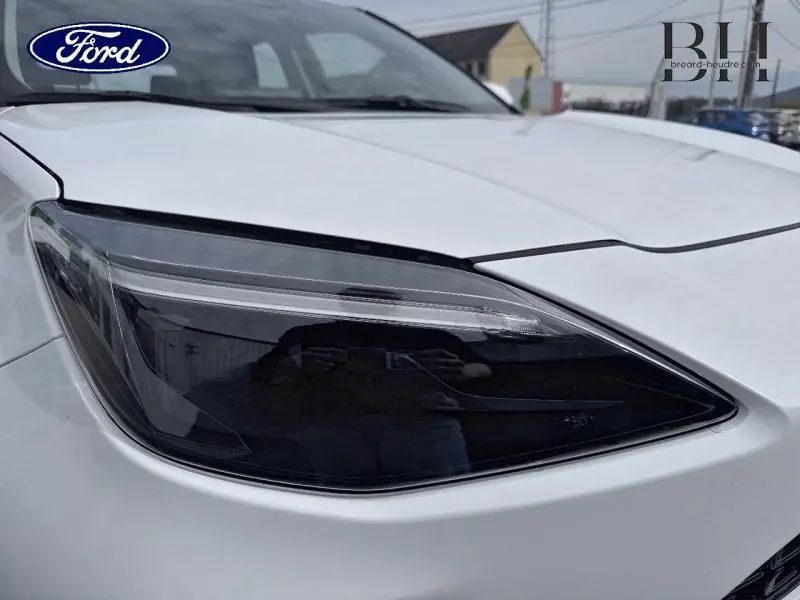 Gros plan sur le phare avant droit noirci d'une Toyota Yaris Cross blanche, soulignant son design moderne et anguleux.