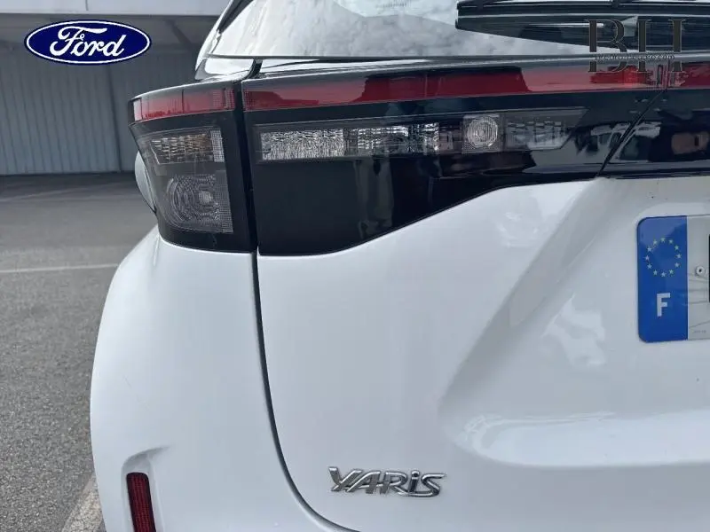 Gros plan sur le feu arrière gauche et le logo Yaris d'une Toyota Yaris Cross blanche vue de l'arrière.