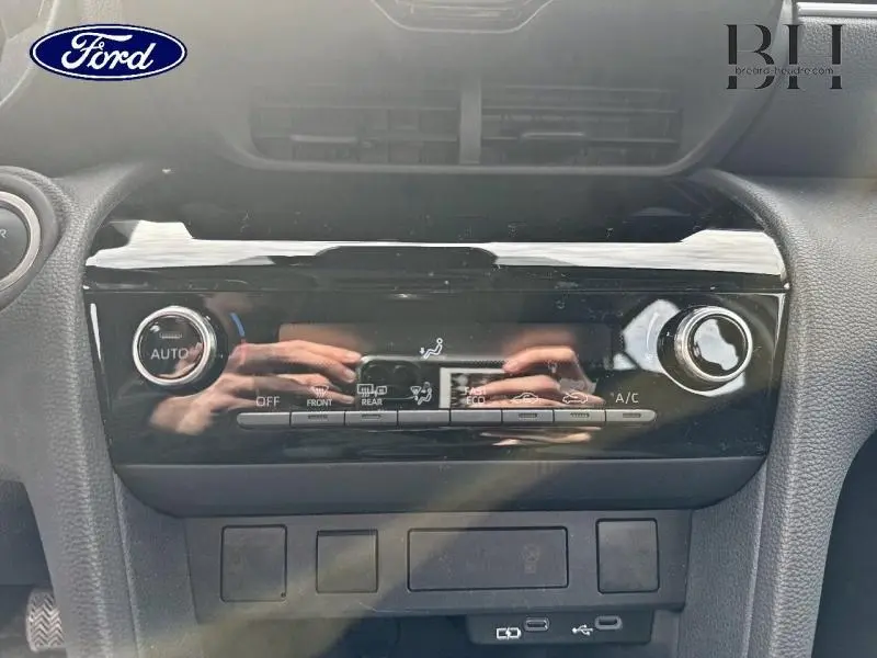 Tableau de bord noir avec commandes de climatisation et ventilation, vue frontale rapprochée intérieure.