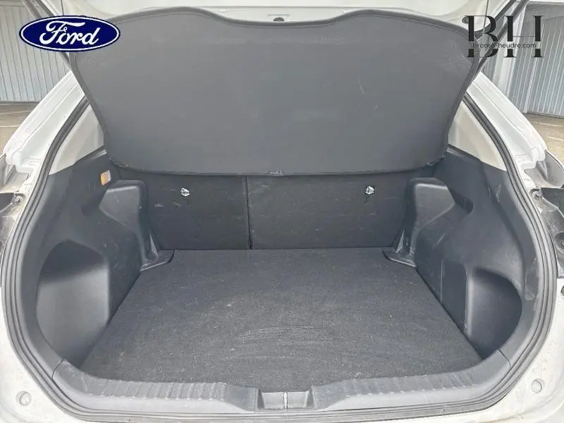 Coffre ouvert vu de l'arrière d'une Toyota Yaris Cross blanc, avec tablette cache-bagages en place.