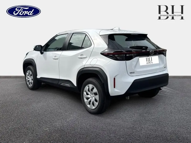 Vue 3/4 arrière droite d'une Toyota Yaris Cross blanche avec protections noires et feux arrière étirés.